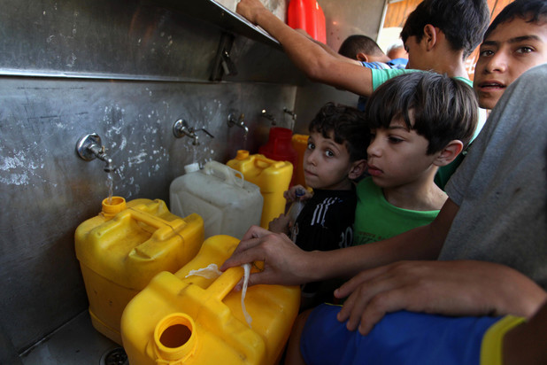 Palestinians children fill plastic bottles and water containers with drinking water from a public tap in Jabalia in the northern Gaza Strip on July 27, 2014. Three Palestinians were killed in shelling as the Israeli military resumed its assault on Gaza after Hamas shunned an extended lull accepted by Israel, medics said. Photo by Ashraf Amra